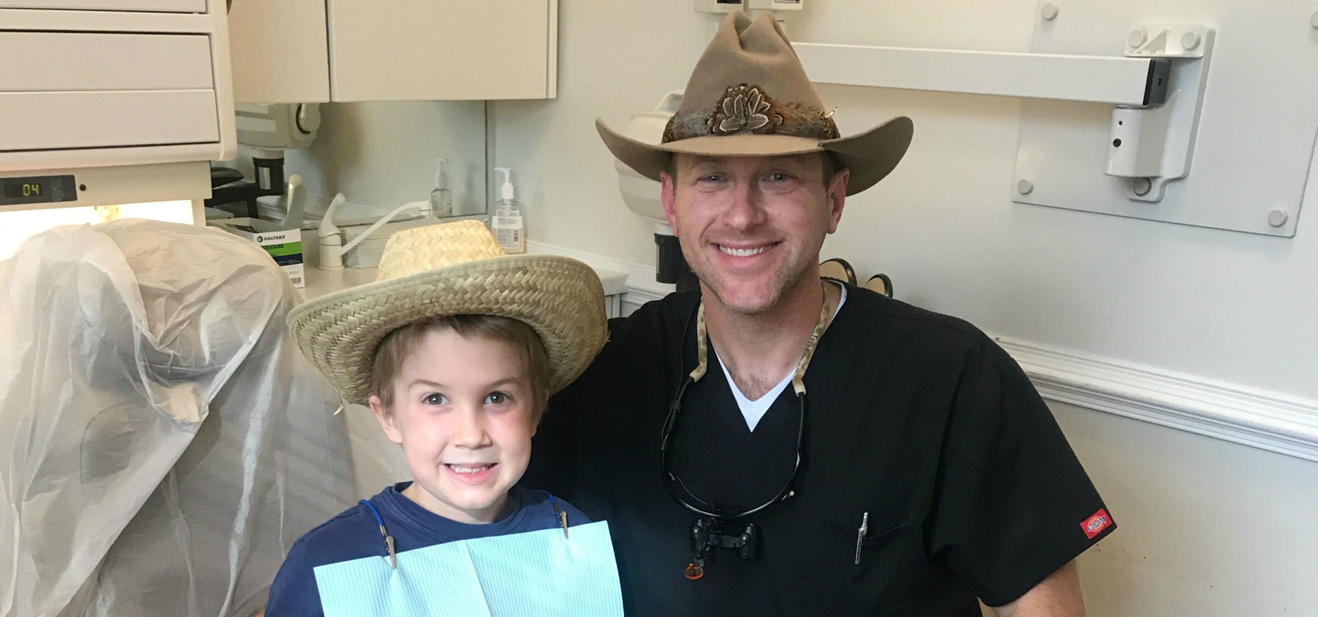 Dr. Bill Argersinger smiling with male pediatric patient while both wearing cowboy hats.