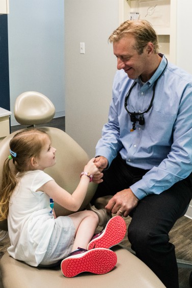 Dr. Bill Argersinger of Durham DDS shaking hands with pediatric female patient.